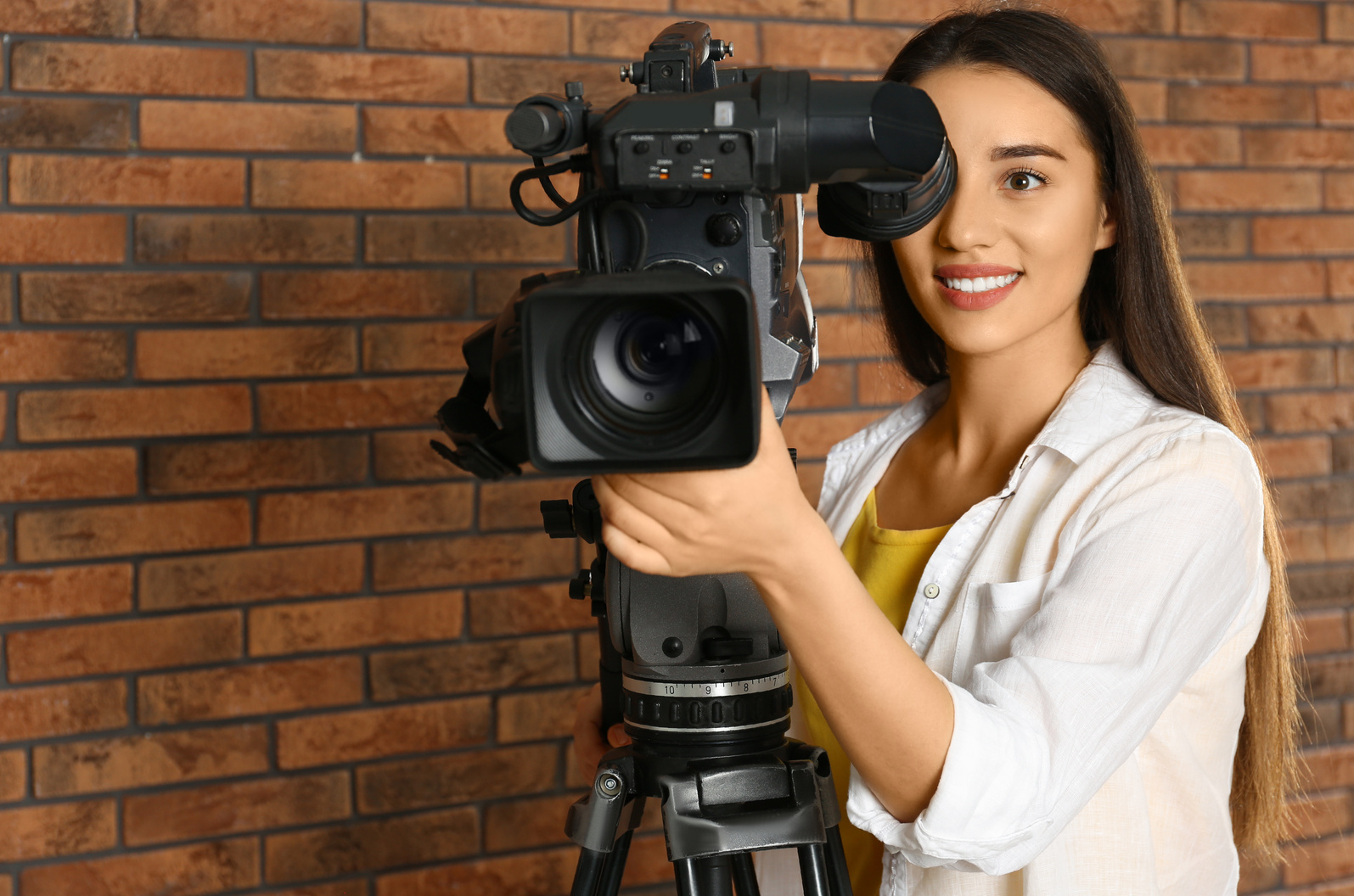 Operator with Professional Video Camera near Brick Wall